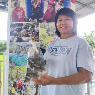 a rural woman farmer happily holding a bag of her newly received fish fry