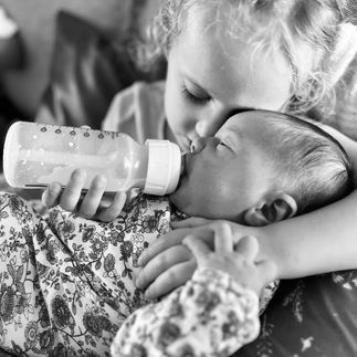 little girl feeding baby a bottle