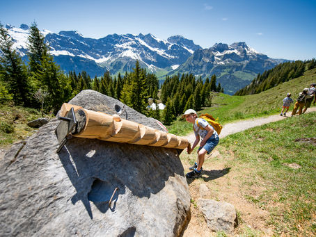 Boy letting a wooden ball run down a ball run through a rock