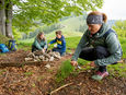 A family making fire at a grill spot on hiking route 4 above Atzmännig