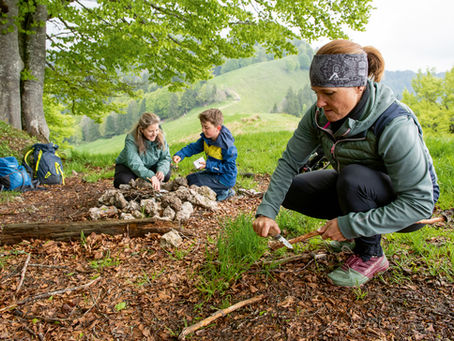 A family making fire at a grill spot on hiking route 4 above Atzmännig