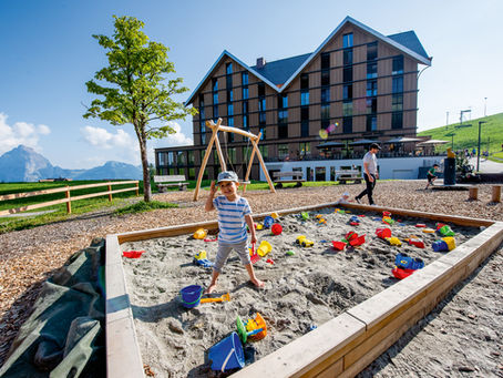 Boy playing in a sandpit outside Stoos Lodge hotel at Stoos