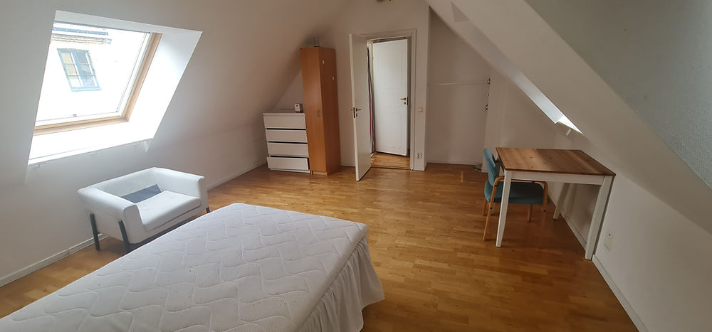 Furnished student room with bed, desk, and wardrobe