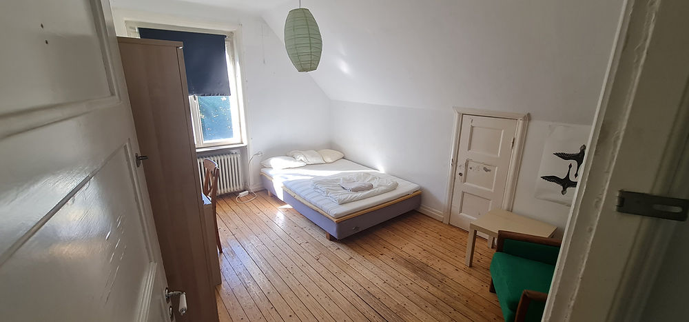 Spacious bedroom with wooden floor, ideal for student housing.