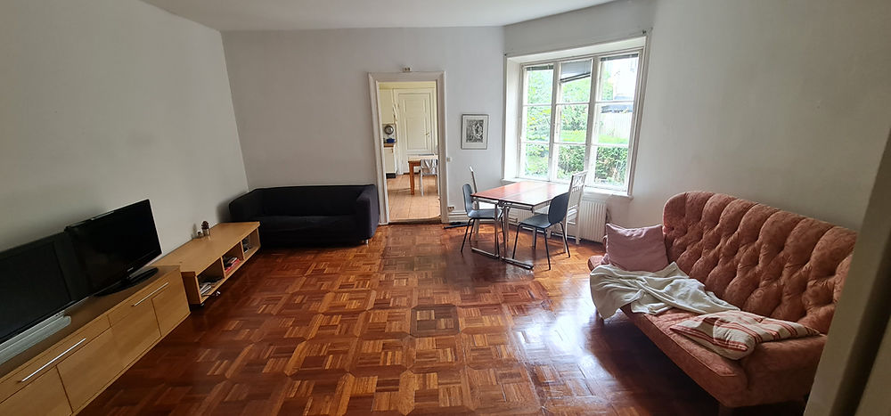 Living room in student housing, with sofas, TV, and dining.