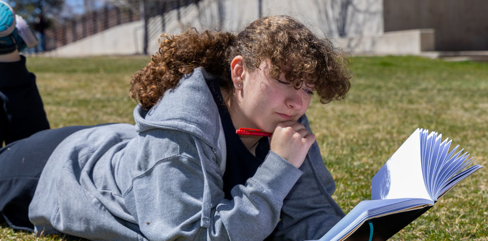 Woman reading book while laying in field