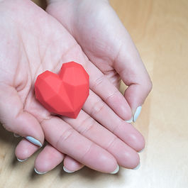 Open hands with a geometric wooden heart inside the palms