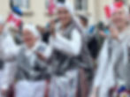 Women in folk costume and rain jackets with Estonian and Canadian flags