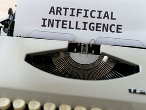 A typewriter with a paper reading "ARTIFICIAL INTELLIGENCE."  Transcribed Text:  ARTIFICIAL INTELLIGENCE
