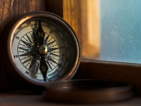 Antique brass compass beside a wooden window frame with frosted glass.