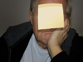 Person with a yellow sticky note on their forehead, resting their head on their hand.
