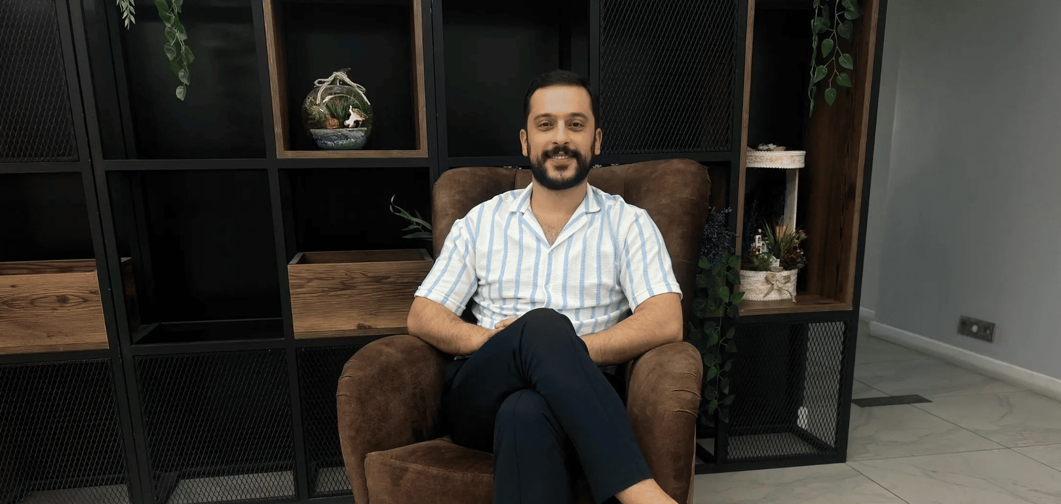 Oturma odasında oturan Psikolog Ahmet Yiğit, gülümseyerek poz veriyor, Tavsiye Benden.