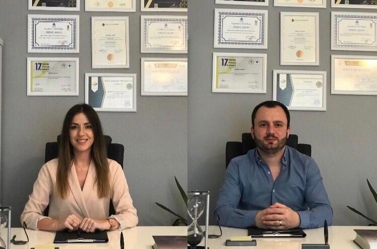 İki kişi ofiste oturuyor, sertifikalarla çevrili, Vadi İnşaat Yapı Yorumları, gülümseyerek poz veriyor.