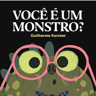 Num fundo preto, um simpático monstro verde usa uma gravata borboleta azul e observa seus óculos redondos, cor de rosa.