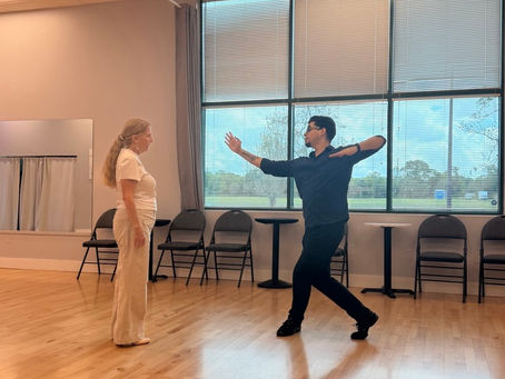 Dance instructor teaching salsa to student in studio.