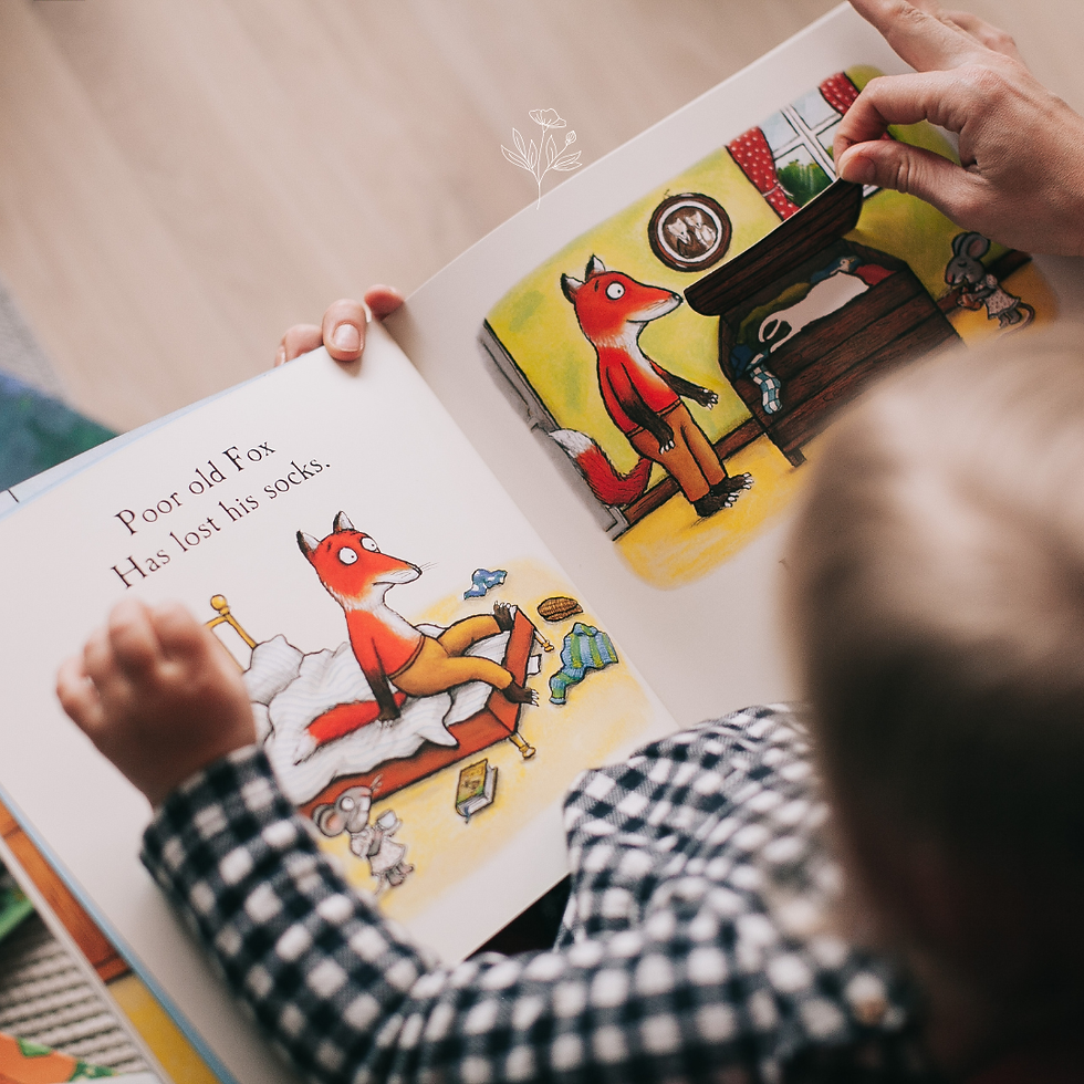 bimbo seduto a leggere una fiaba e la mano di un adulto che lo aiuta