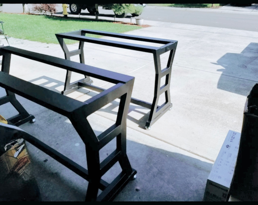 Powder-coated metal table base with custom side detailing and a sleek, modern profile, awaiting tabletop installation.