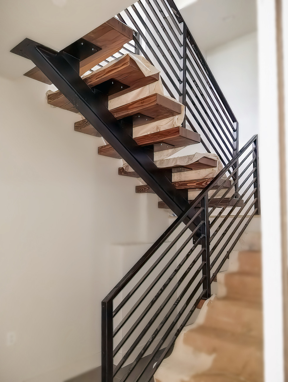 Custom modern mono-beam staircase with single stringer, part of a collaborative three-staircase installation by NW Metalworks and local wood artisan.