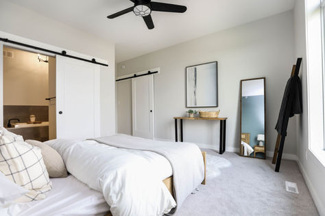 Primary bedroom at 3 Benjamin Boulevard with wood bed frame, blue accent wall, barn door ensuite entry, and carpeted flooring.