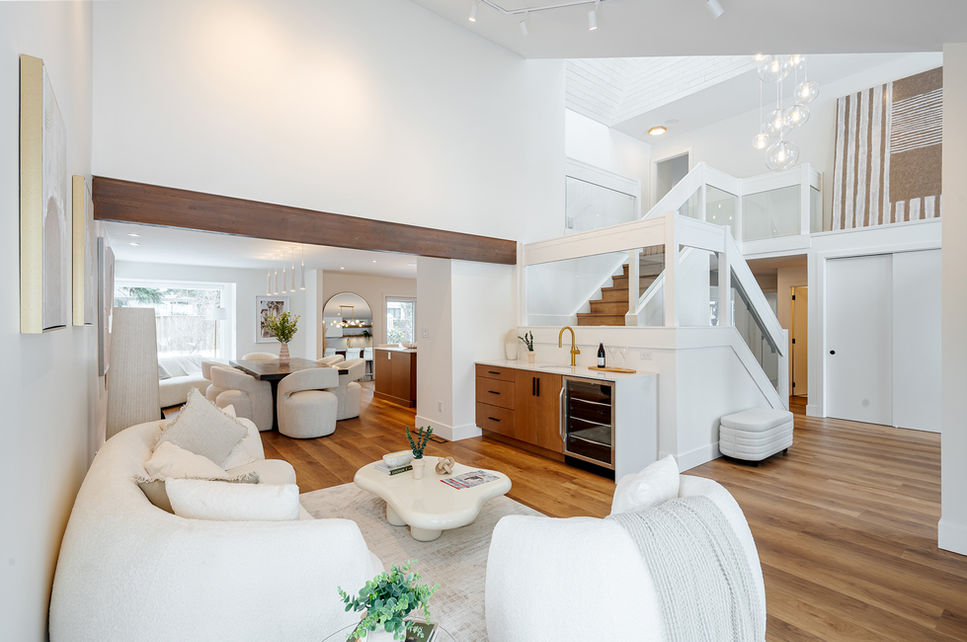 Living room at 67 Dunbar Crescent with curved sofa, wet bar, staircase, and bright open layout.