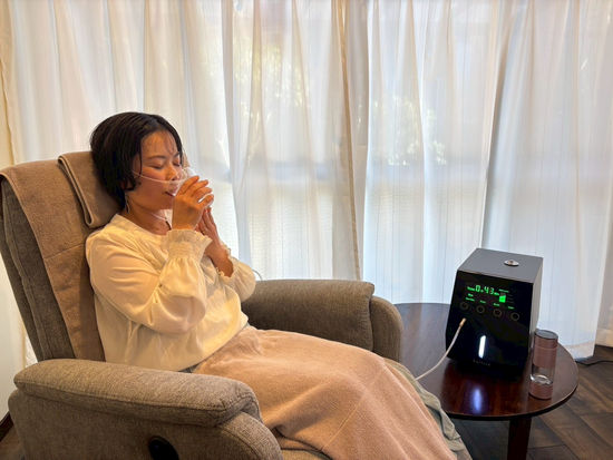 女性がリクライニングチェアでくつろぎ、水素吸入器を使用中
