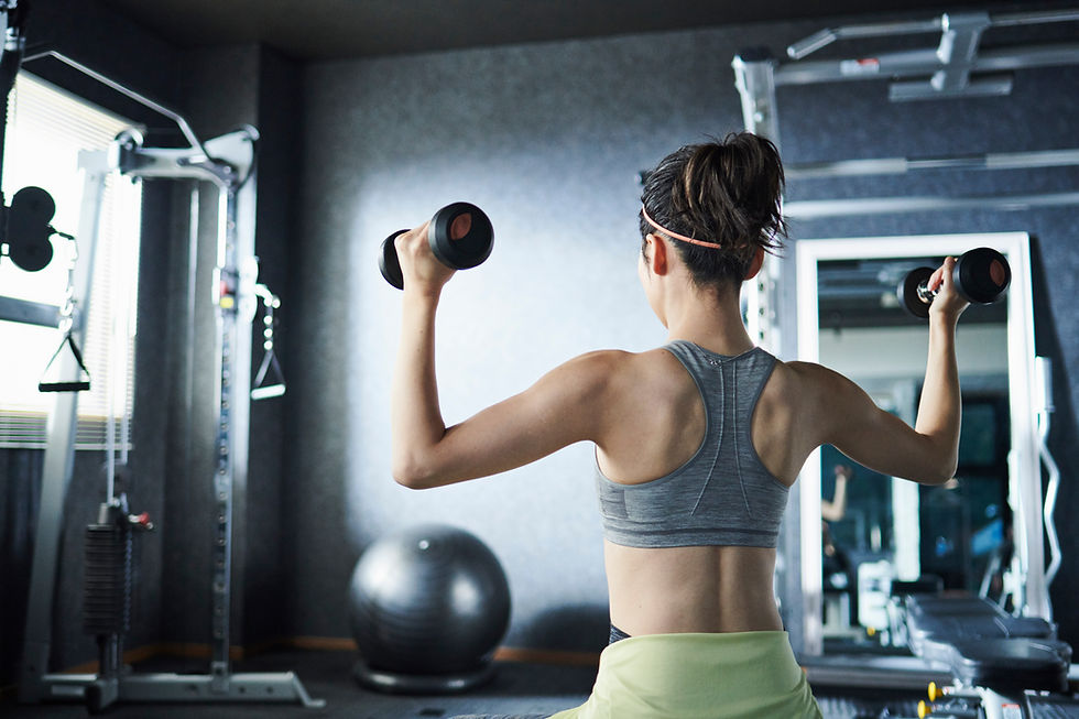 女性がダンベルを持ち、トレーニングをしています。ジムでの運動風景。