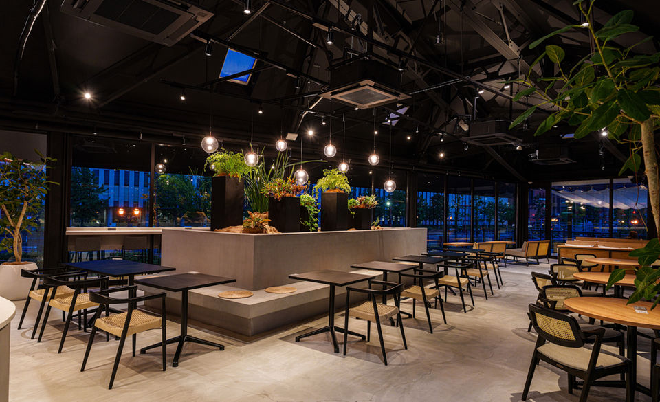 夜のモダンなカフェ、植物と照明が飾られた広々とした空間