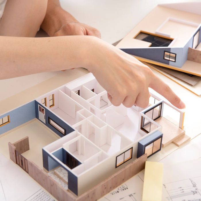 誰かの手は、家モデルを指しています。建築家が設計図を検討しています。