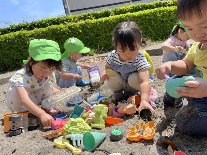 砂場で遊ぶ子供たち、様々な色の砂場用おもちゃ。武の子保育園で楽しそうに遊んでいます。