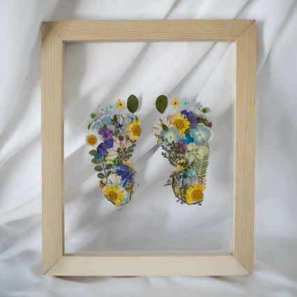 FLORALCHEMY FLORAL PRESERVATION. ST, PETE, FL. NATURAL HANDMADE FRAME WITH MULTI-COLORED FLOWER MIX IN SHAPE OF BABY FEET. FLORAL FOOTPRINTS. 