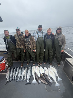Group of guests posing with their catch in front of an Alaska fishing lodge after a successful day on the water.
