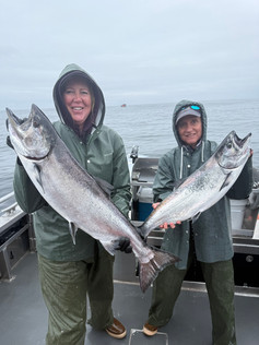Group of guests posing with their catch in front of an Alaska fishing lodge after a successful day on the water.