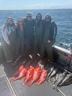 Smiling family showing off their catch together in front of an Alaska fishing lodge, enjoying a fun and memorable day outdoors