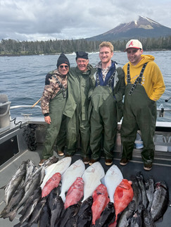 Smiling family showing off their catch together in front of an Alaska fishing lodge, enjoying a fun and memorable day outdoors