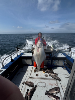 Smiling family showing off their catch together in front of an Alaska fishing lodge, enjoying a fun and memorable day outdoors