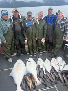 Group of guests posing with their catch in front of an Alaska fishing lodge after a successful day on the water.