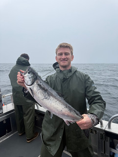 Smiling family showing off their catch together in front of an Alaska fishing lodge, enjoying a fun and memorable day outdoors