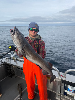 Smiling family showing off their catch together in front of an Alaska fishing lodge, enjoying a fun and memorable day outdoors