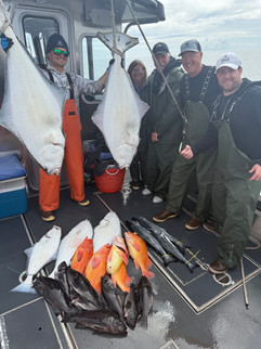 Group of guests posing with their catch in front of an Alaska fishing lodge after a successful day on the water.
