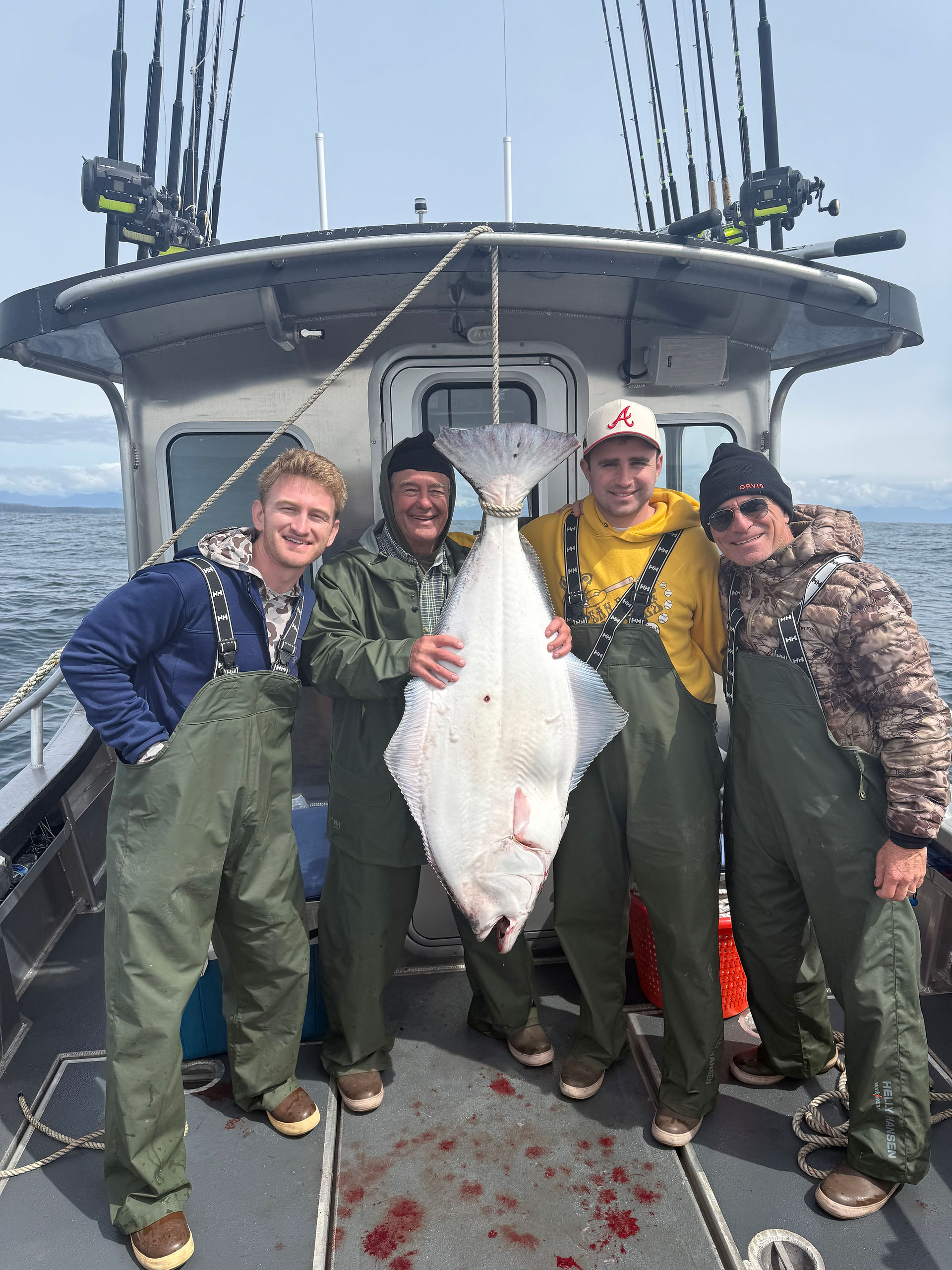 Smiling family showing off their catch together in front of an Alaska fishing lodge, enjoying a fun and memorable day outdoors