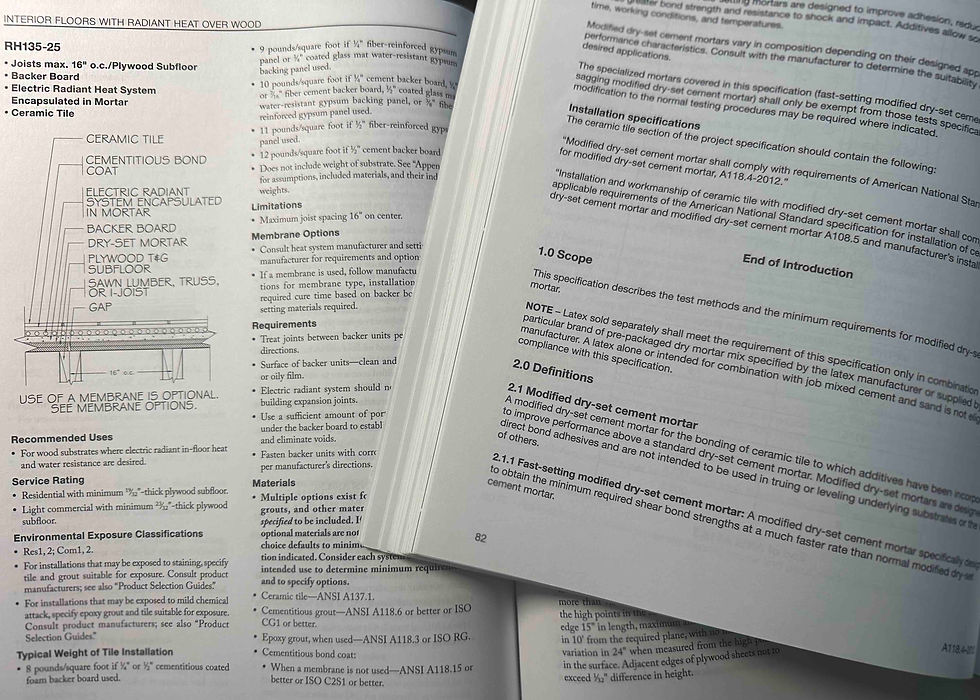 Open construction manual showing text and diagrams about radiant heat flooring over wood. Pages include specs, definitions, and requirements.