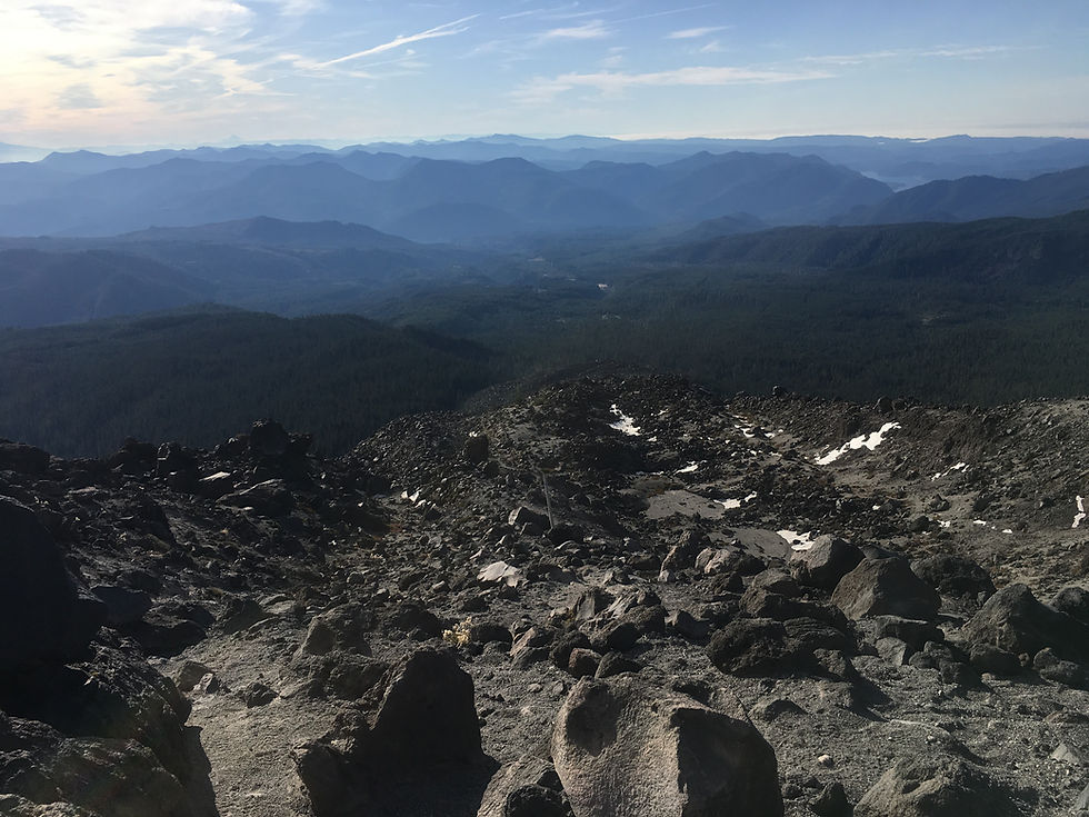 looking down the boulder field filled with sharp black rocks with ridges on ridges layering in the background