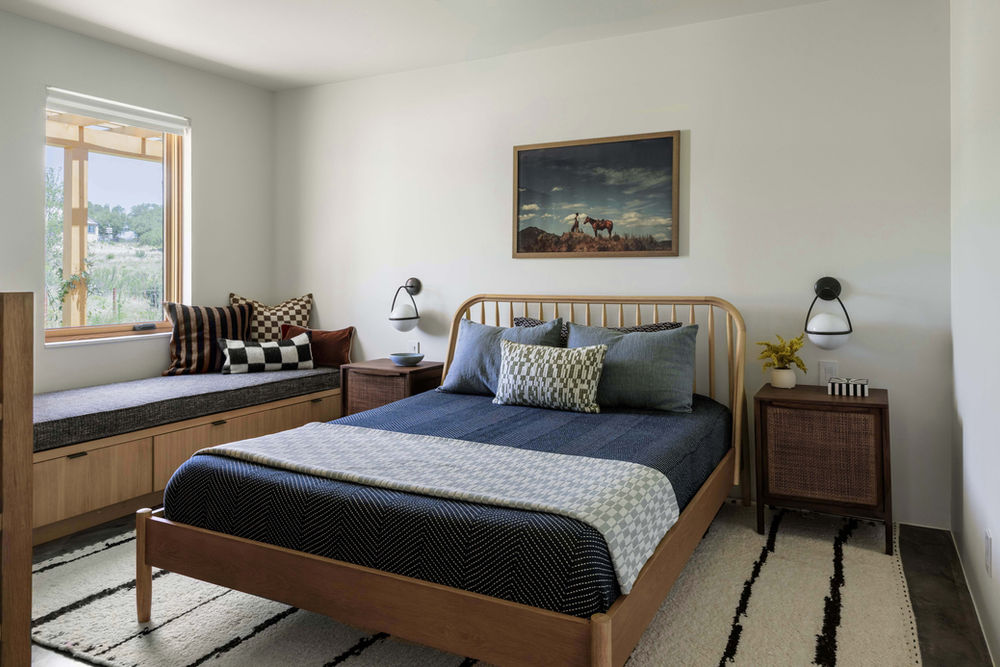 A guest bedroom design in a Hill Country ranch theme with cowboy art and decorated with textured, earthy accent pillows.