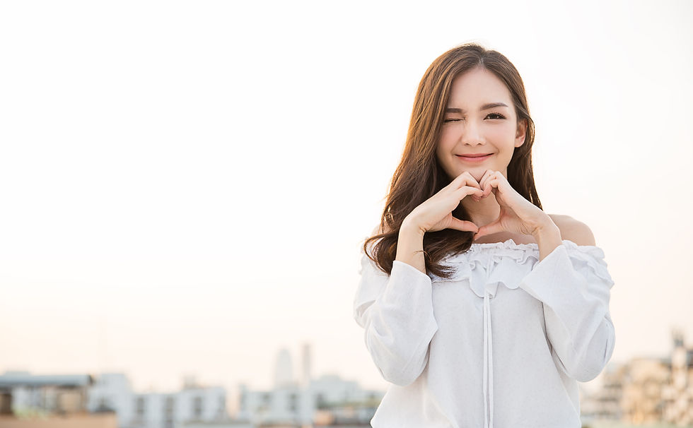 Portrait of young beautiful asian woman hands gesture in heart shape on city sky roof top.