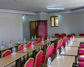 Pazuri Hotel conference room set up with red chairs, water bottles, and presentation space