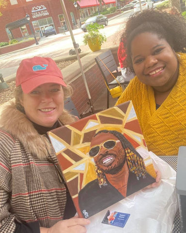 Artist Shakeyla Shinholster meets with a client to drop off a custom painting of Stevie Wonder. 