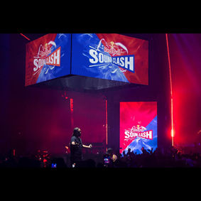 Vue de la scène opposée, avec un autre artiste en pleine performance, tandis que les écrans suspendus et au fond de la scène affichent des visuels dynamiques du RedBull Soundclash. La scénographie immersive crée une ambiance de compétition captivante.