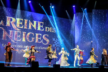 Un groupe de danseurs en costumes fantastiques évolue sur scène, accompagné de décors projetés représentant un paysage enneigé. Cette scène transporte le public dans un monde hivernal et fantastique, avec des effets visuels qui renforcent l’ambiance immersive.