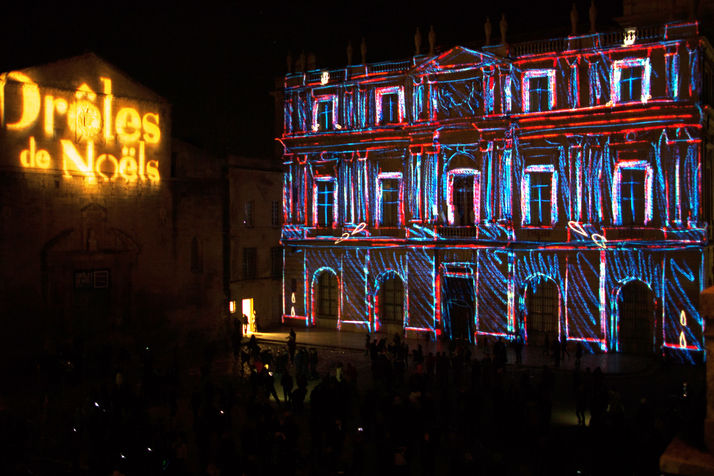 Projection de couleurs vives et formes géométriques illuminant la façade de la mairie d’Arles pour le festival Drôles de Noëls.