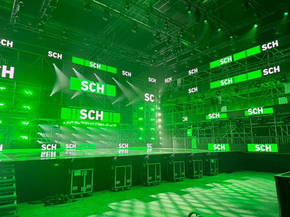 Un large écran LED vert affichant le nom "SCH" domine la scène de la phase finale de Nouvelle École. Studio ENORME a conçu des visuels dynamiques synchronisés pour sublimer les performances des artistes lors de ce concours de rap diffusé sur Netflix.